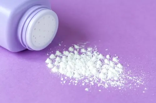 White powder spilled from a lavender plastic container on a purple surface.