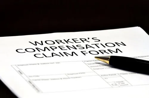 Close-up of a worker's compensation claim form with a black pen resting on top.