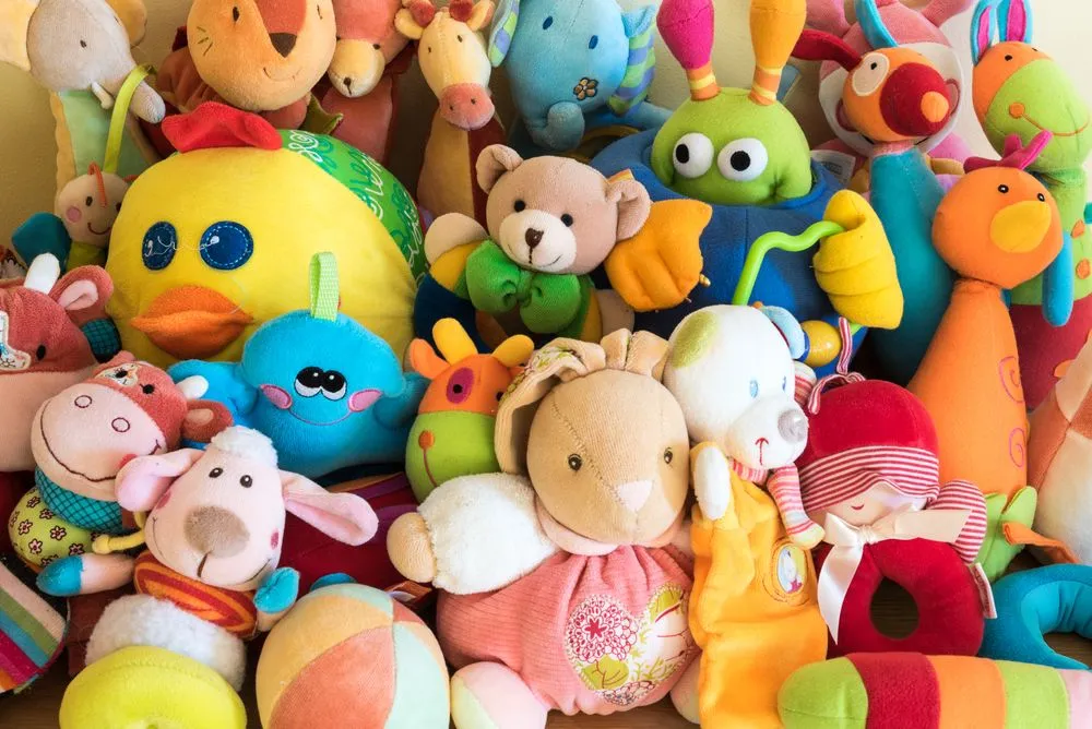 Colorful assortment of various plush toys including animals, a doll, and a ball.
