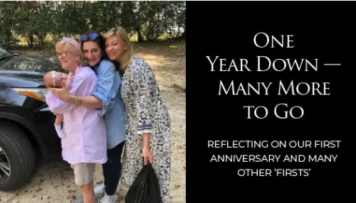 Three women embracing outdoors beside a black vehicle; text reads "One Year Down — Many More to Go" and anniversary message.