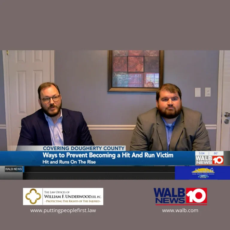 Two men in suits seated indoors during a news segment on preventing hit and run incidents.