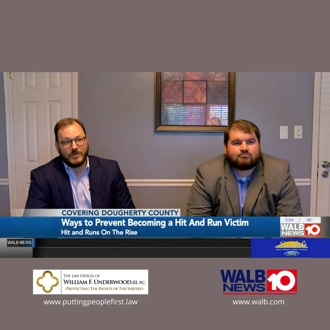 Two men in suits seated indoors during a news segment on preventing hit and run incidents.