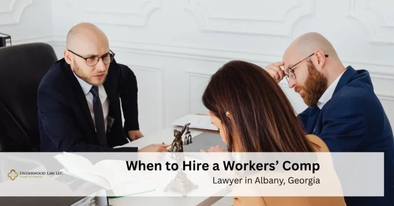 Two men in suits consulting with a woman at a desk with legal documents, statue, and text overlay about hiring a workers' compensation lawyer.