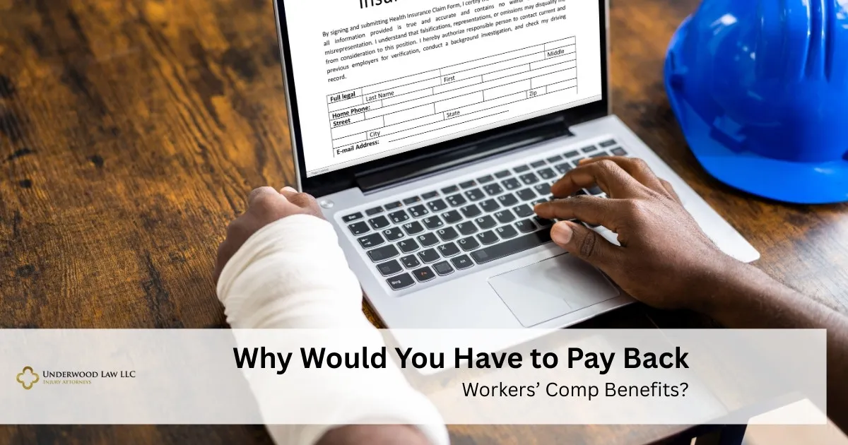 Person with bandaged arm filling out an insurance claim form on a laptop, blue safety helmet nearby.