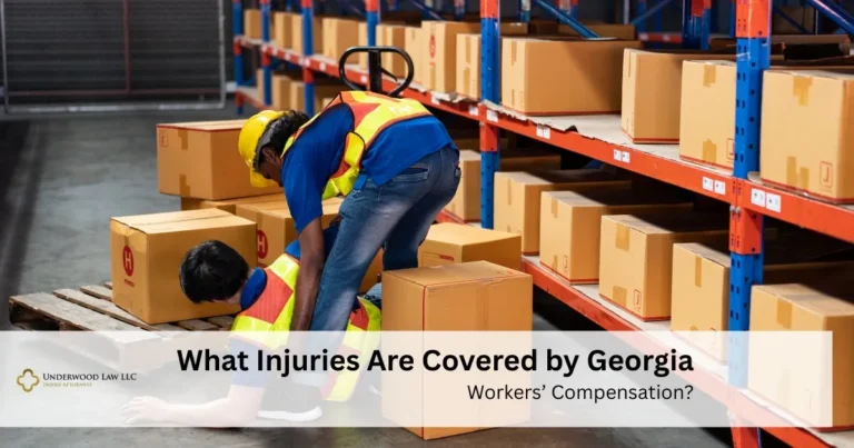 Two warehouse workers in safety vests and helmets, one helping the other who fell among stacked cardboard boxes.