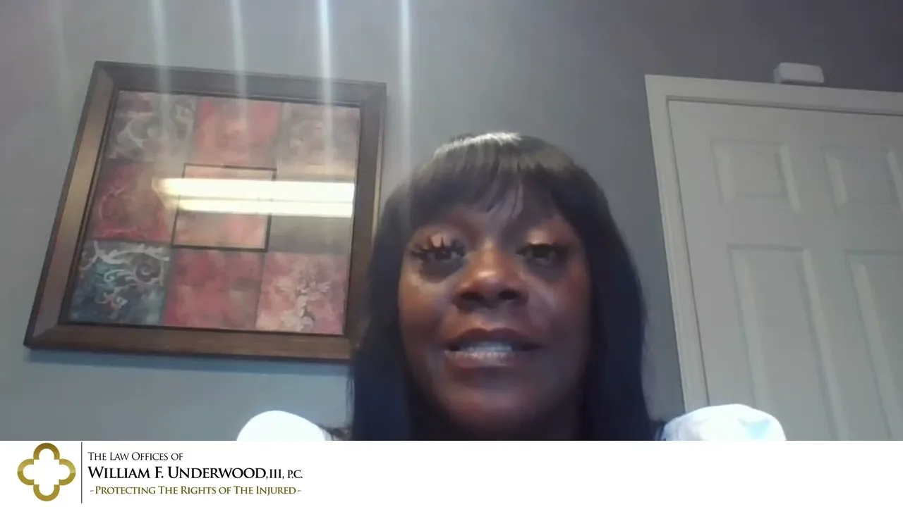 Woman with long black hair speaking in a video call, framed artwork and white door in background.