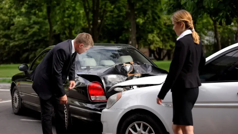 Two formally dressed individuals inspecting damage after a car collision in a parking lot.