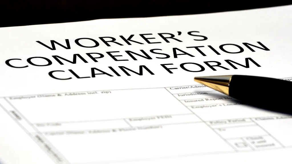 Close-up of a worker's compensation claim form with a black and gold pen resting on it.