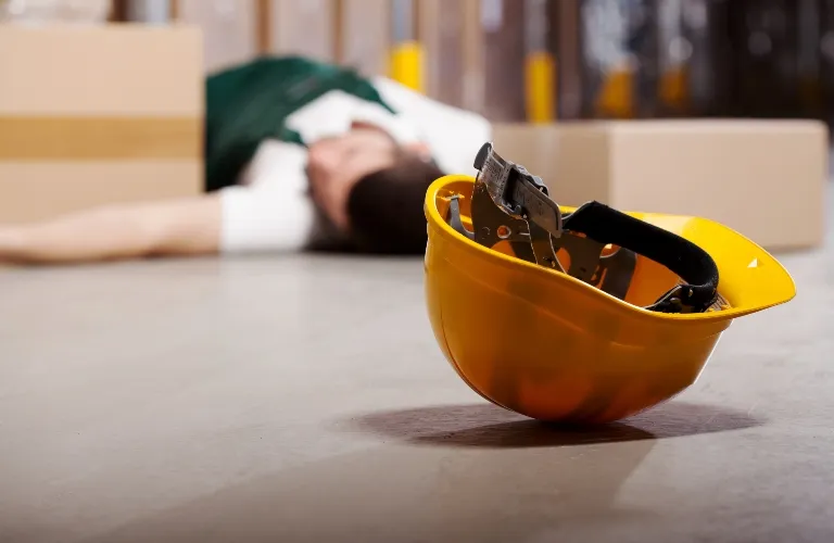 Yellow construction helmet on floor in foreground, blurred person lying down in background.