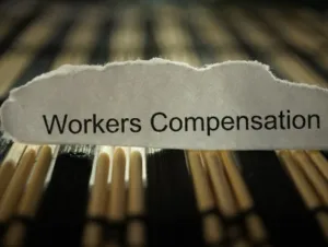 Torn paper with "Workers Compensation" text resting on wooden matches background.